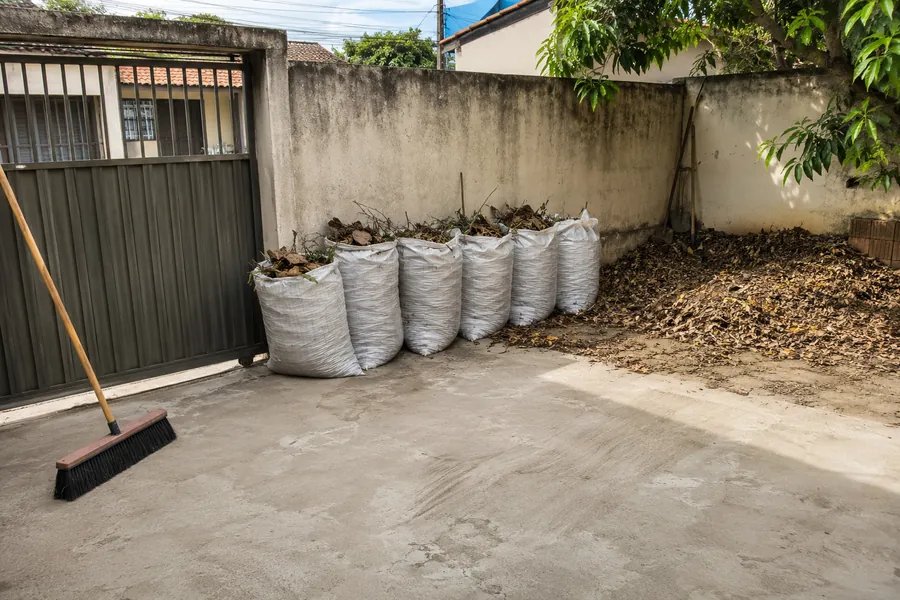 Quintal residencial limpo, com folhas e entulho ensacados